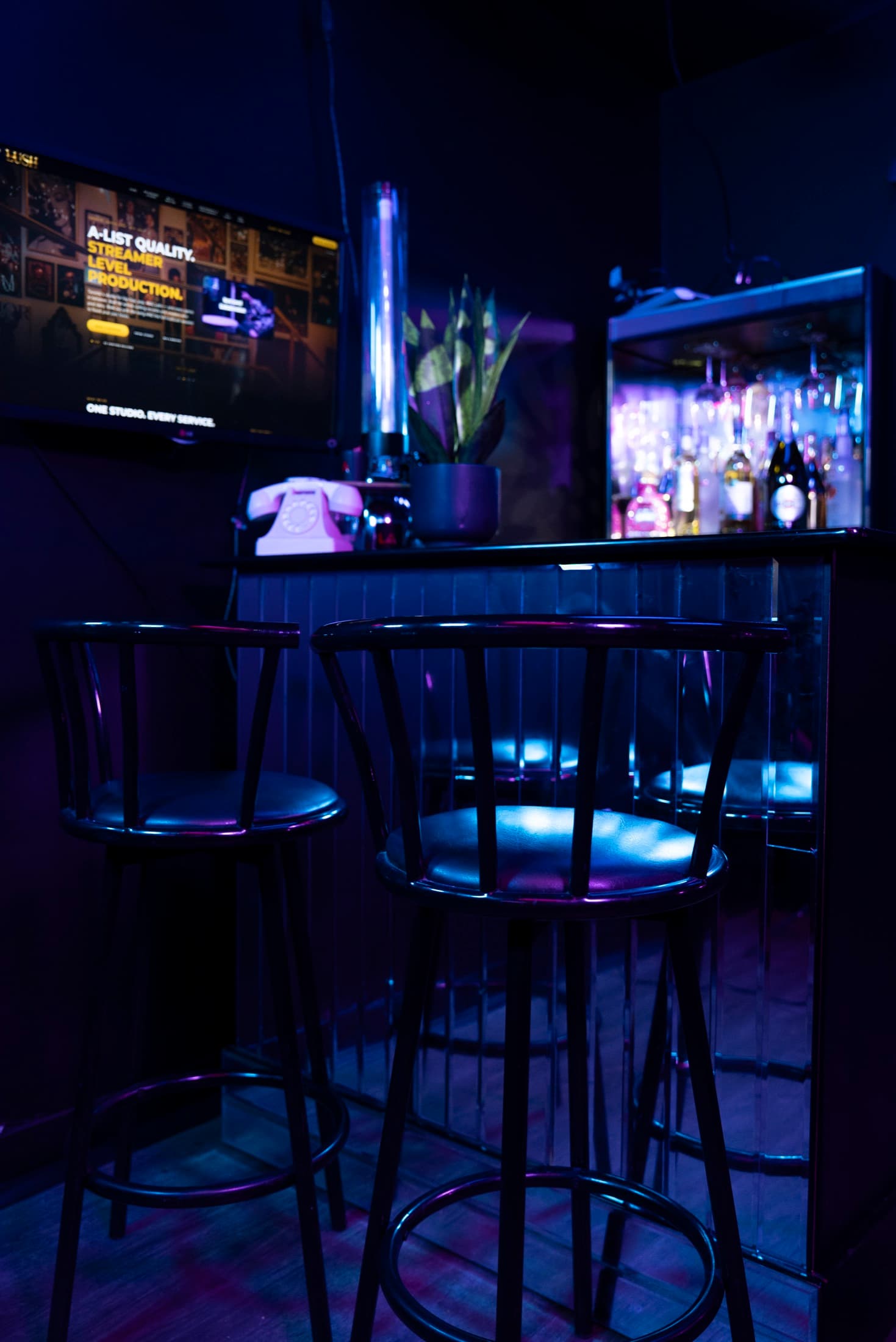 Bar stools at Lush Event Space with backlit spirits shelf behind