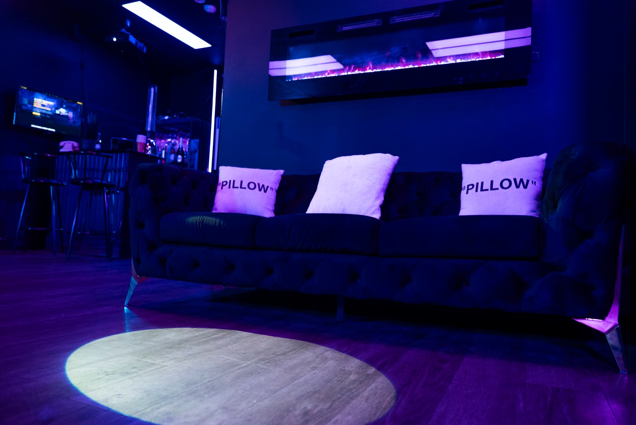 Lush Event Space lounge — velvet seating beneath the fireplace in violet light