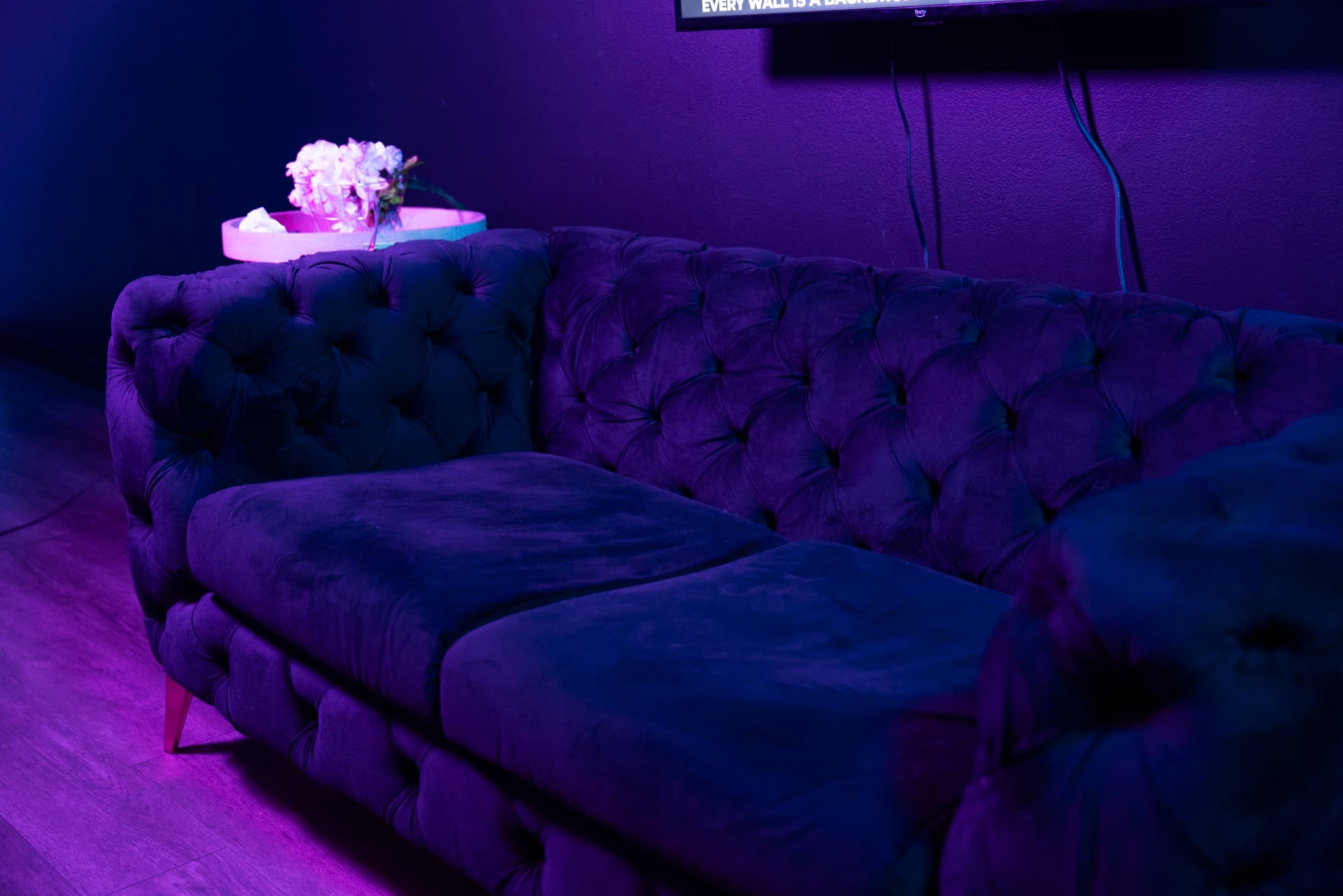 Velvet sectional lounge with flowers under purple light