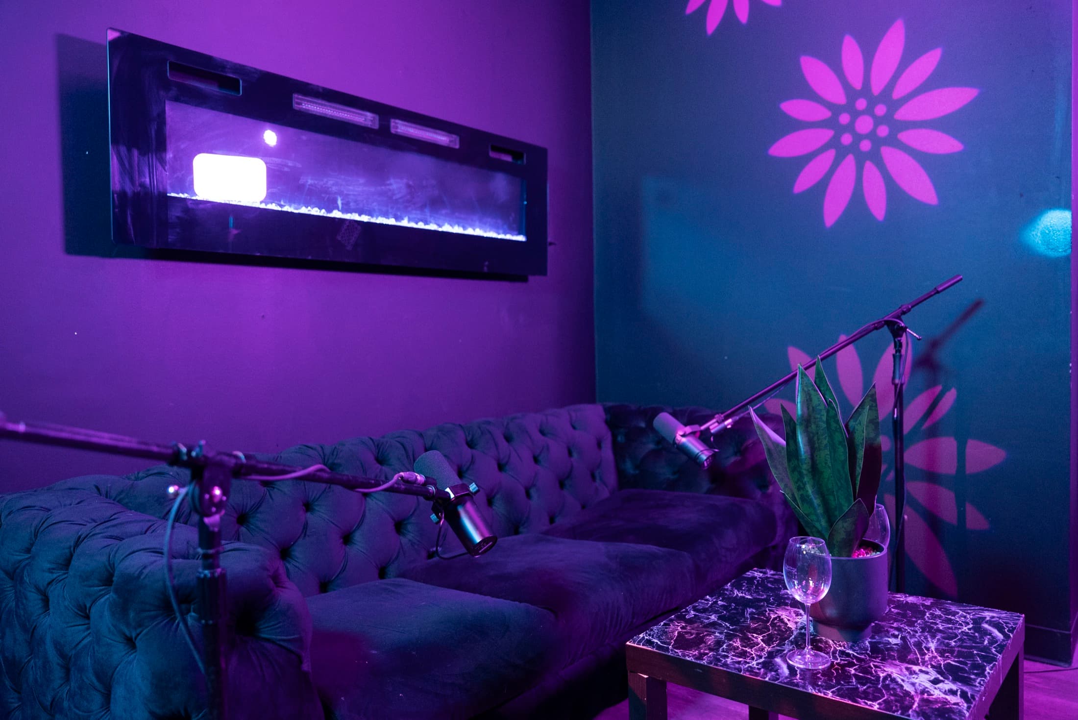 Podcast set at Lush Event Space — fireplace wall, velvet sectional, boom mics, floral light projections